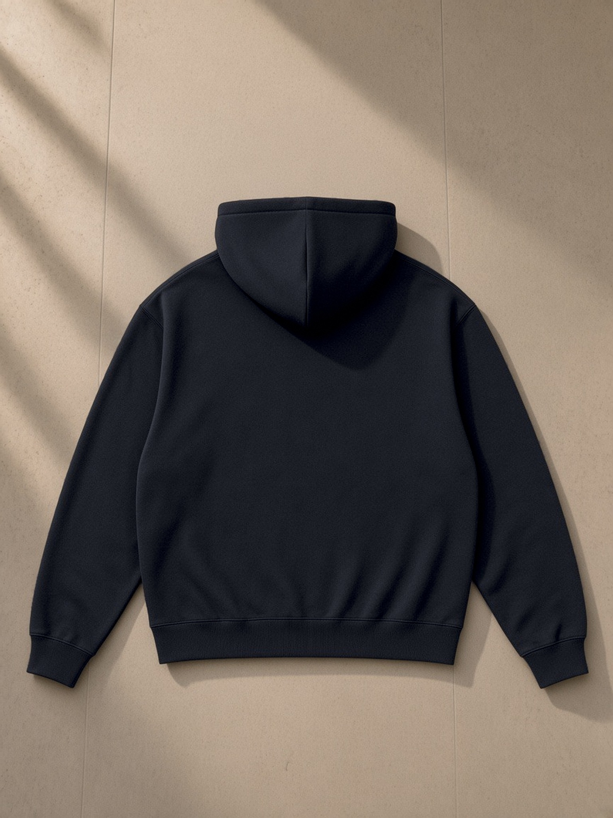 Essential Heavyweight Drop-Shoulder Hoodie in Navy Blue, laid flat on pale limestone, back view