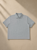 Cropped polo shirt in Gray, laid flat on pale limestone