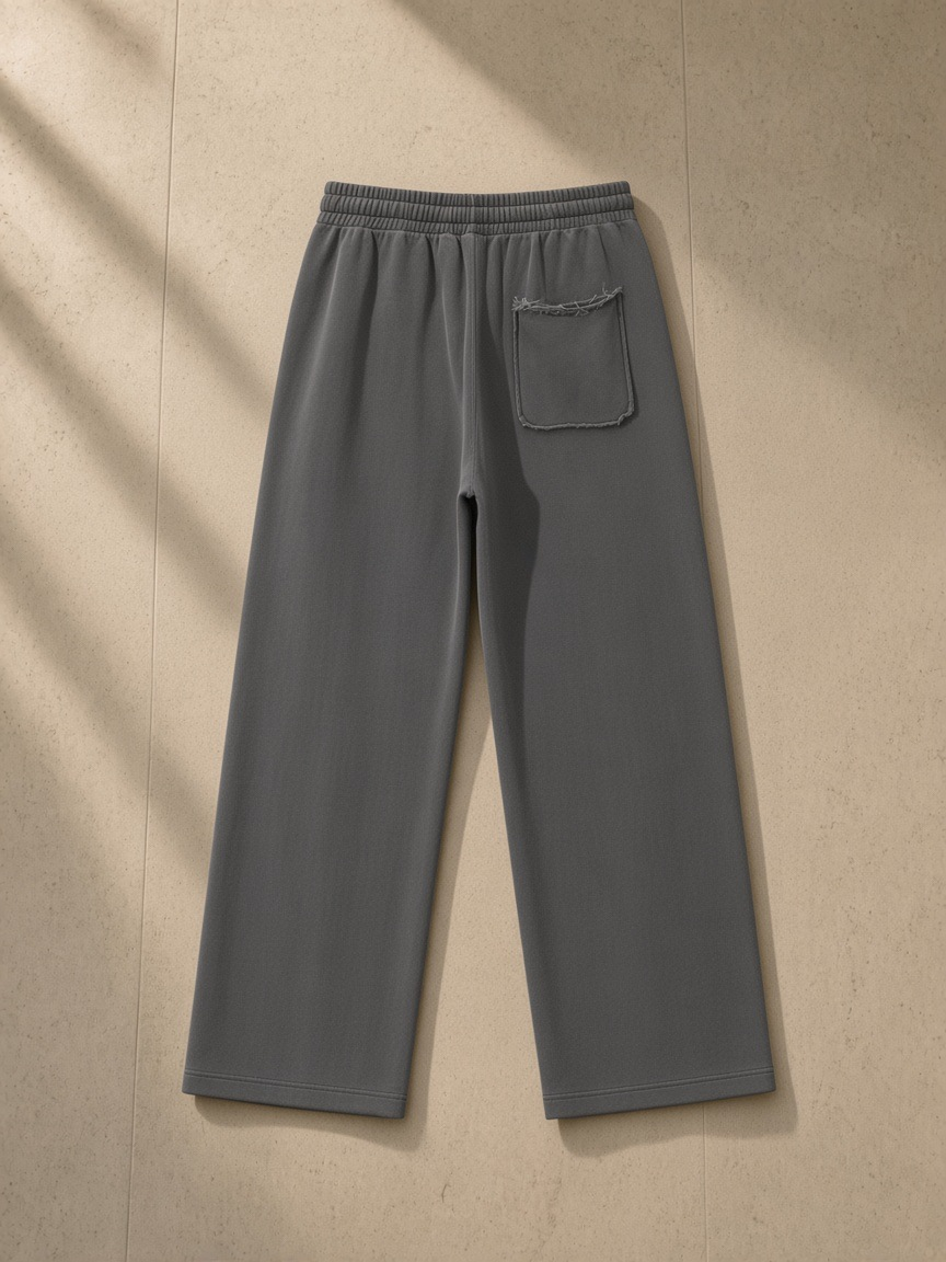 Snow Washed Raw Edge Sweatpants in Dark Gray, laid flat on pale limestone, back.