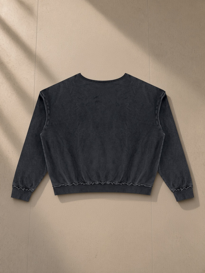 Raw edge crewneck sweatshirt in Black, laid flat on pale limestone, back view