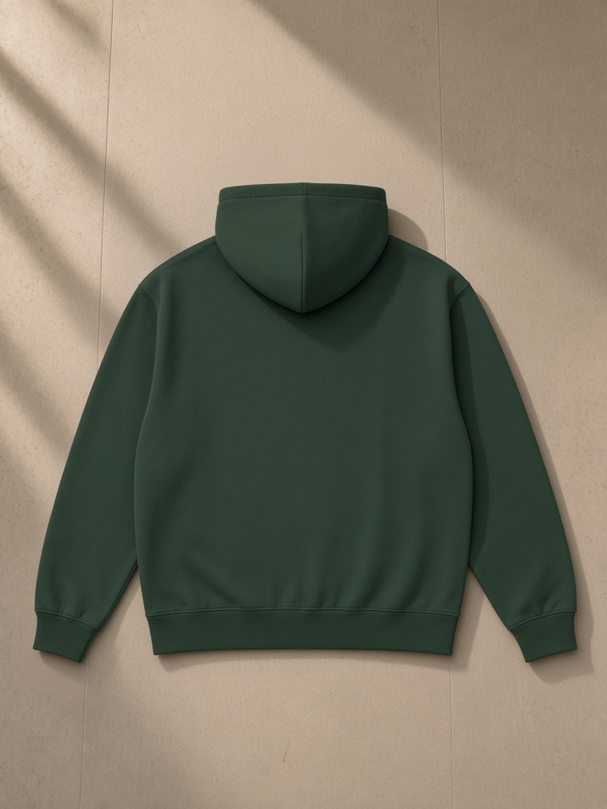 Heavyweight pullover hoodie in Blackish Green, laid flat on pale limestone, back view