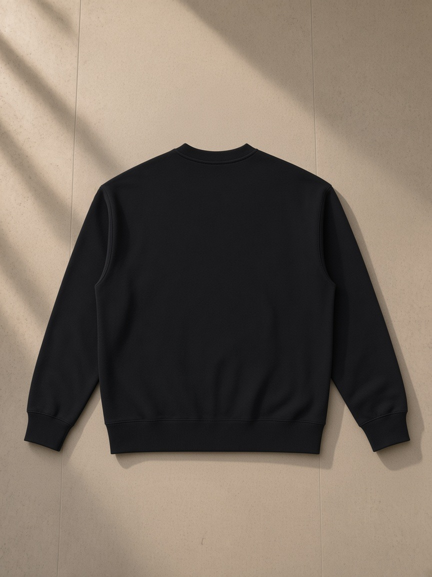 Heavyweight patch pocket crewneck sweatshirt in Black, laid flat on pale limestone, back view