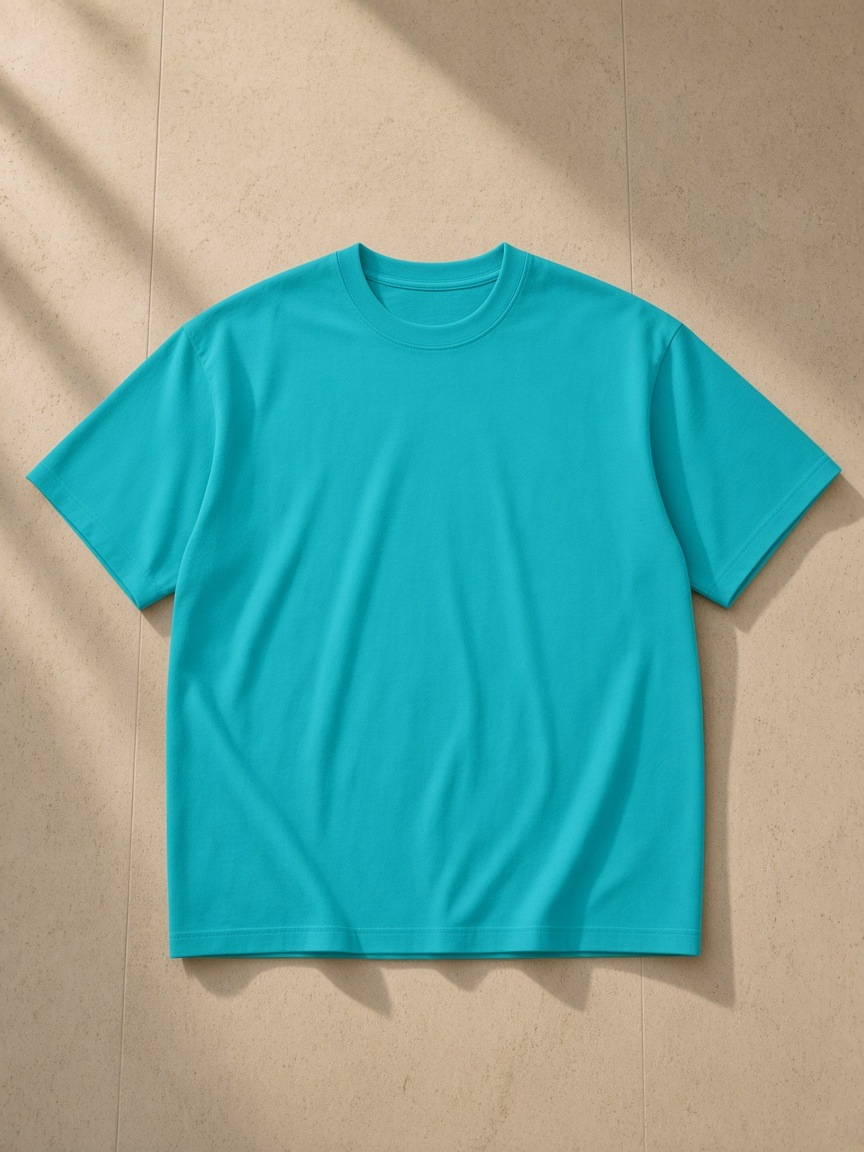 Unisex oversized drop shoulder t-shirt in Lake Blue, laid flat on pale limestone