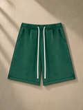 Unisex vintage wash fleece shorts in Dark Green, laid flat on pale limestone