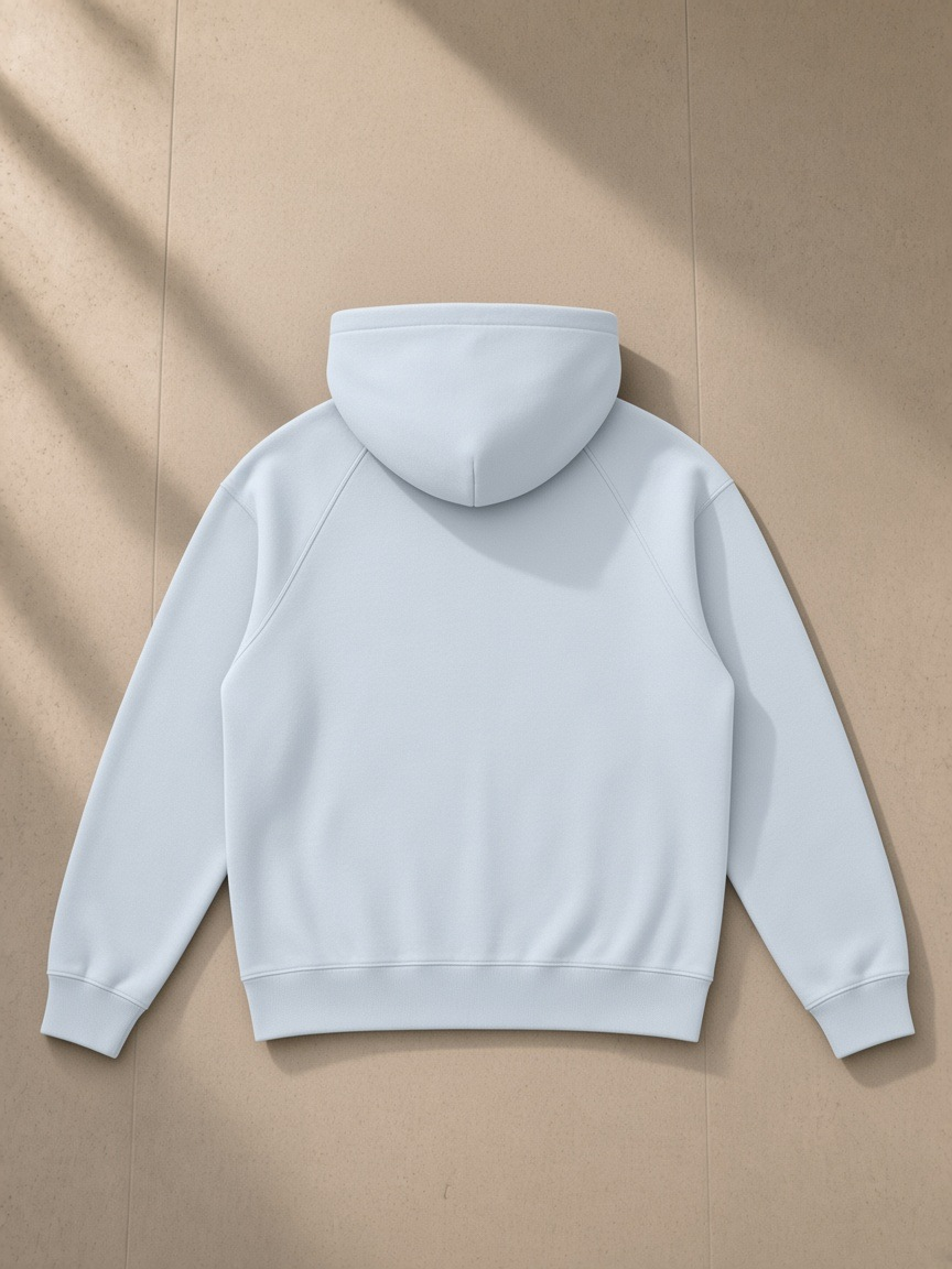 Raglan full zip hoodie in Light Blue, laid flat on pale limestone, back view