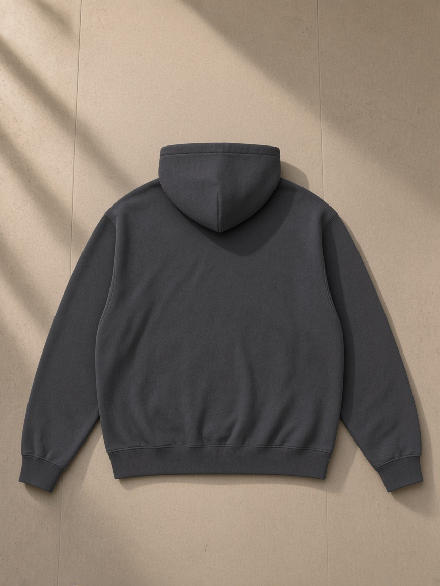 Unisex heavyweight zip-up hoodie in Dark Gray, laid flat on pale limestone, back view