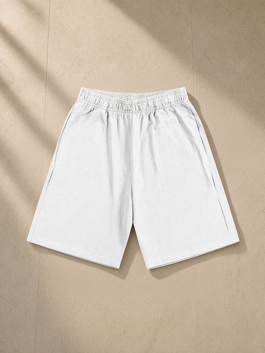 Unisex heavyweight cotton shorts in White, laid flat on pale limestone