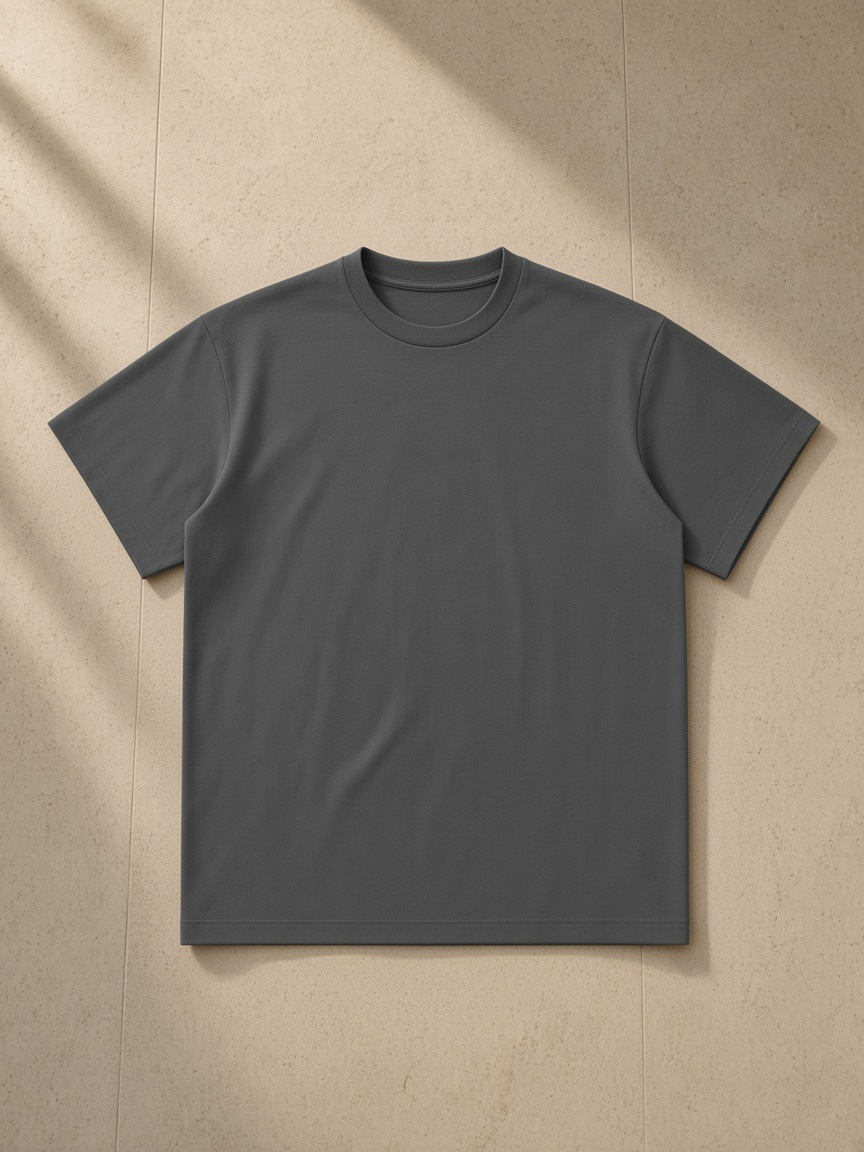 Unisex Lightweight Oversized T-Shirt in Charcoal Gray, laid flat on pale limestone