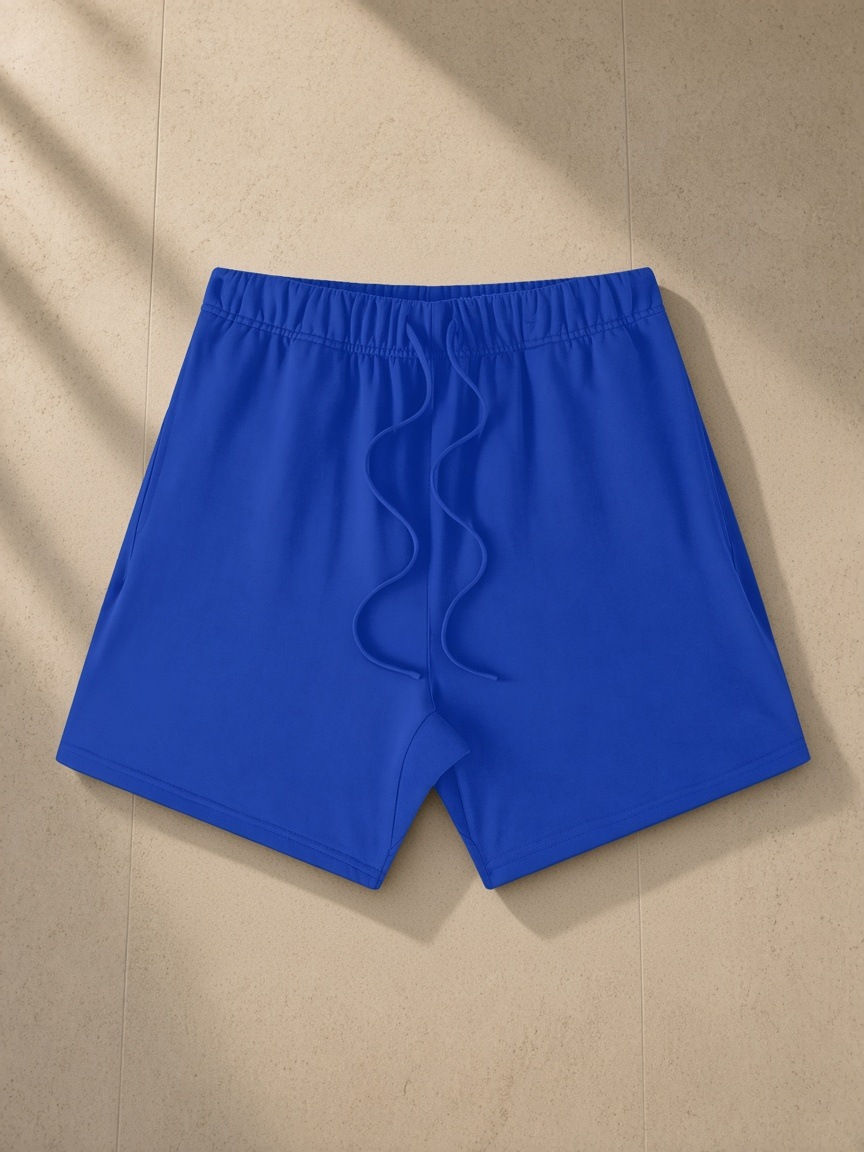Earth Tone Loose Fit Cotton Shorts in Colorful Blue, laid flat on pale limestone