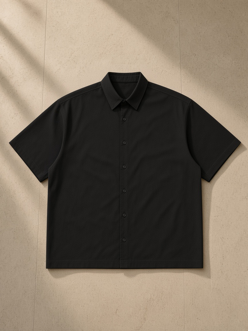 Boxy Short Sleeve Shirt in Black, laid flat on pale limestone