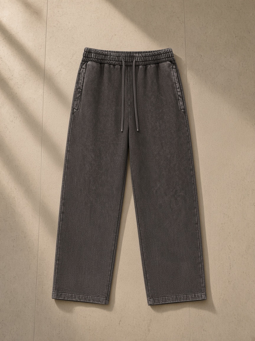 Unisex snow wash heavyweight sweatpants in Dark Gray, laid flat on pale limestone