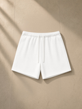 Unisex fleece drawstring sweatshorts in White, laid flat on pale limestone