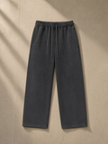 Unisex snow wash heavyweight sweatpants in Black, laid flat on pale limestone