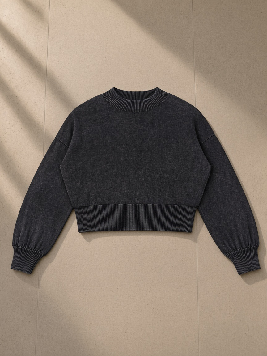 Women's Balloon Sleeve Cropped Sweater in Black, laid flat on pale limestone