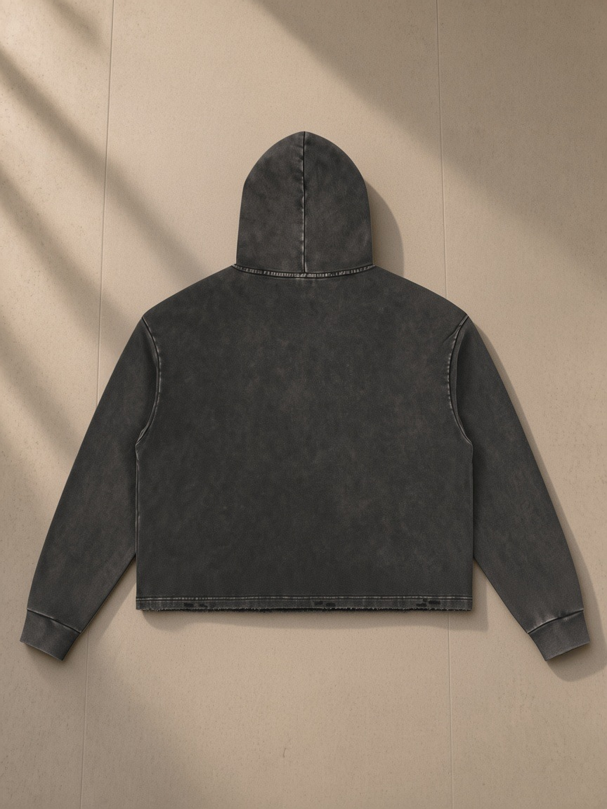 Vintage washed frayed-hem hoodie in Black, laid flat on pale limestone, back view