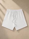 Earth Tone Loose Fit Cotton Shorts in White, laid flat on pale limestone
