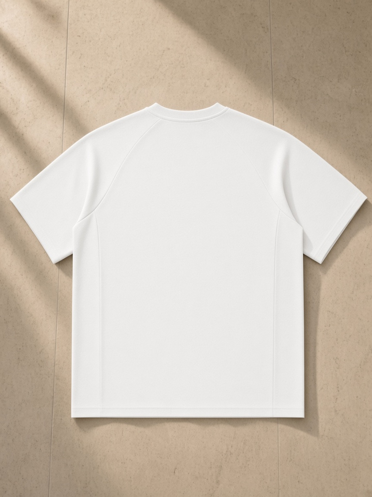 Oversized Paneled Raglan T-Shirt in White, laid flat on pale limestone, back.