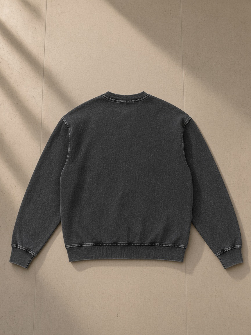 Unisex snow wash oversized crewneck sweatshirt in Black, laid flat on pale limestone, back view