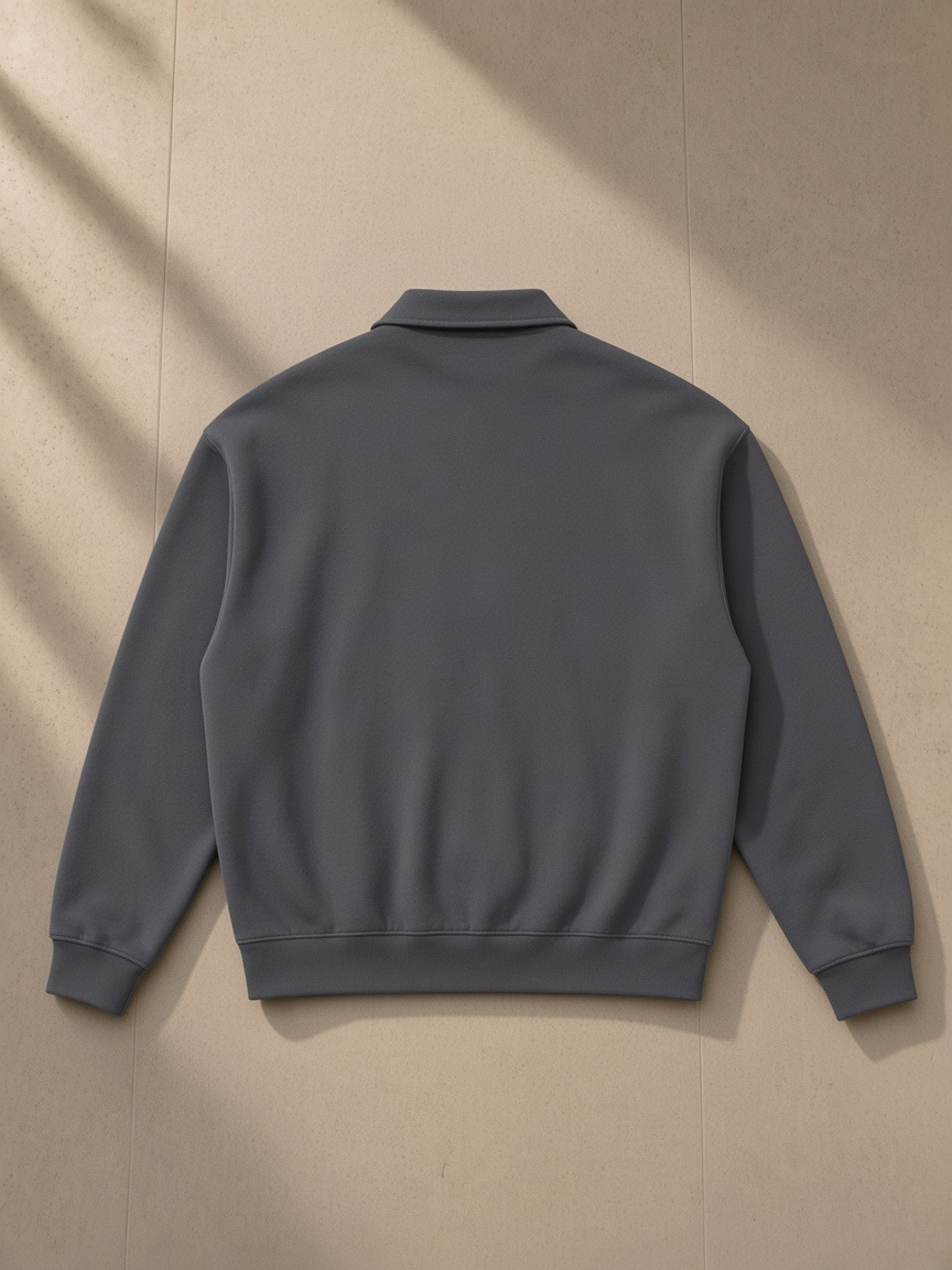 Heavyweight fleece polo sweatshirt in Charcoal Gray, laid flat on pale limestone, back view
