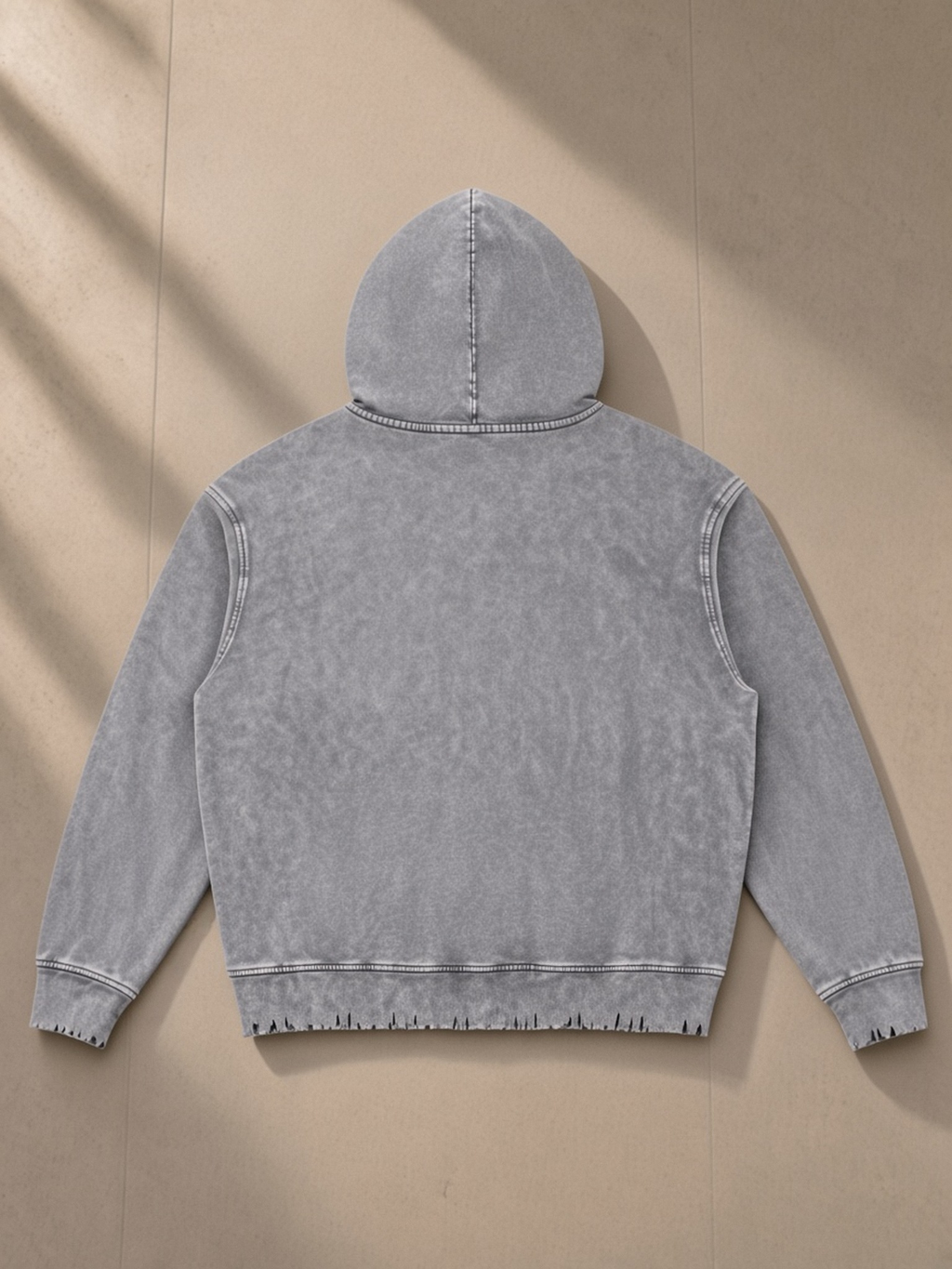 Snow Wash Hand-Frayed Heavyweight Hoodie in Light Gray, laid flat on pale limestone, back.