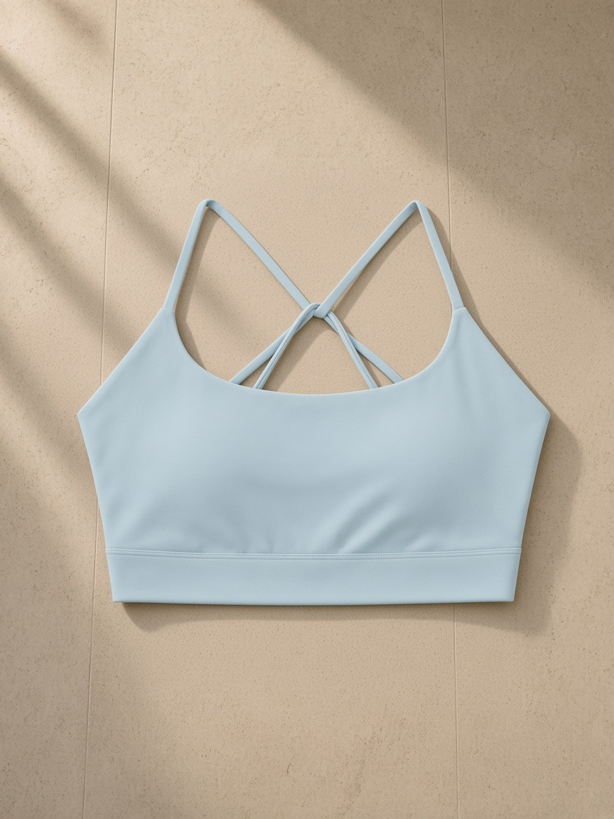 Strappy Criss Cross Yoga Sports Bra in Light Blue, laid flat on pale limestone