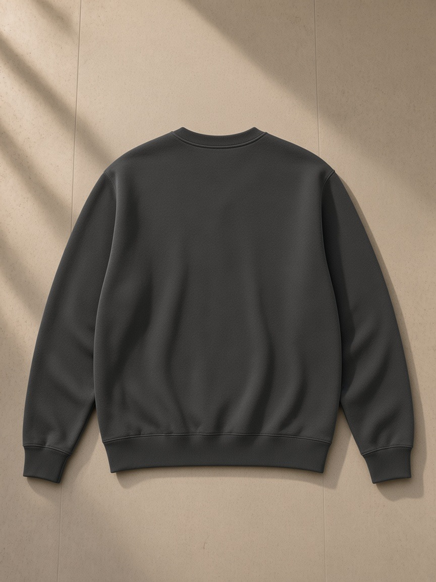 Unisex heavyweight crewneck sweatshirt in Dark Gray, laid flat on pale limestone, back view