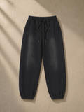 Unisex vintage washed fleece jogger sweatpants in Black, laid flat on pale limestone