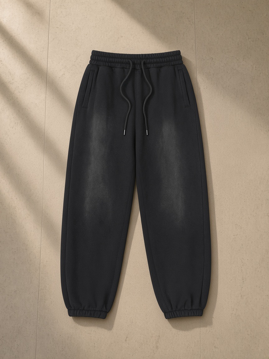 Unisex vintage washed fleece jogger sweatpants in Black, laid flat on pale limestone