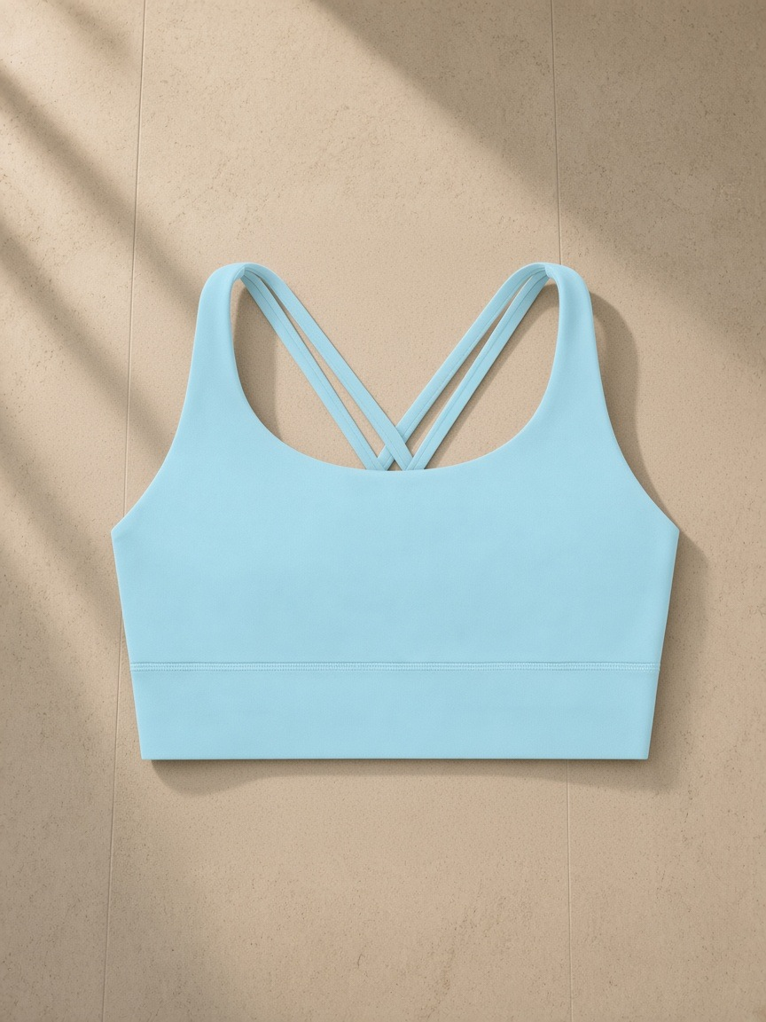 Strappy criss-cross sports bra in Light Blue, laid flat on pale limestone