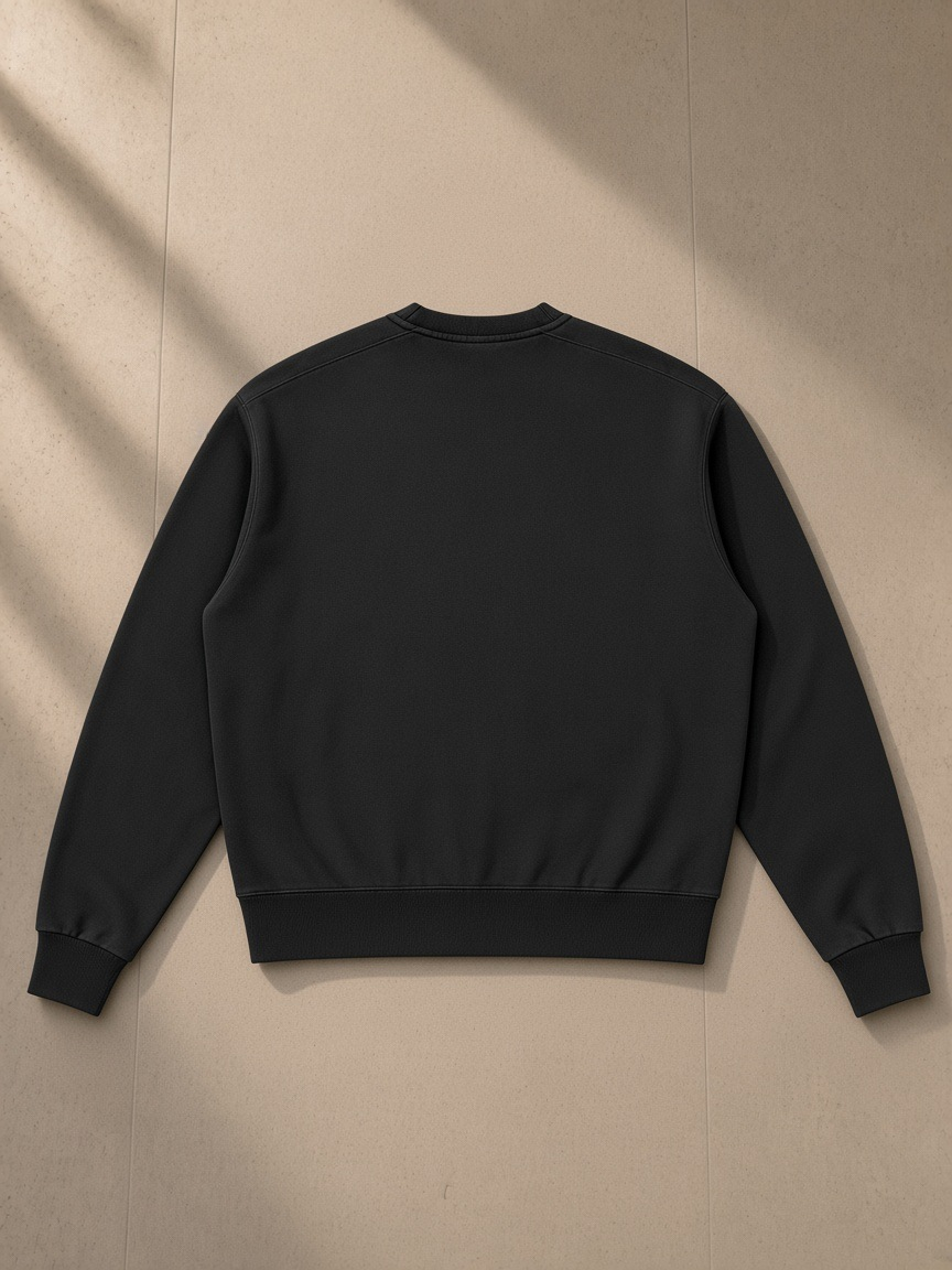 Unisex vintage wash crewneck sweatshirt in Black, laid flat on pale limestone, back view