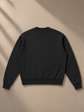 Unisex vintage wash crewneck sweatshirt in Black, laid flat on pale limestone, back view