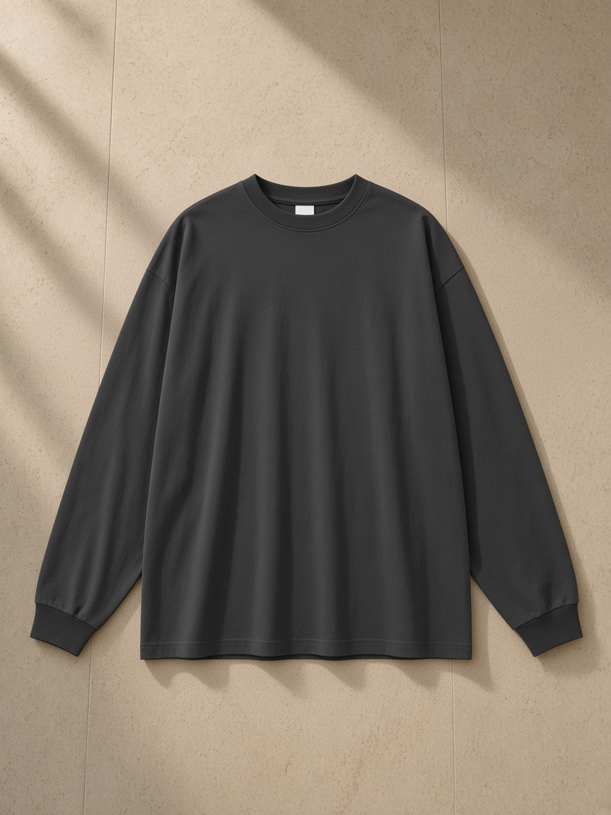 Oversized Long Sleeve T-Shirt in Carbon Gray, laid flat on pale limestone