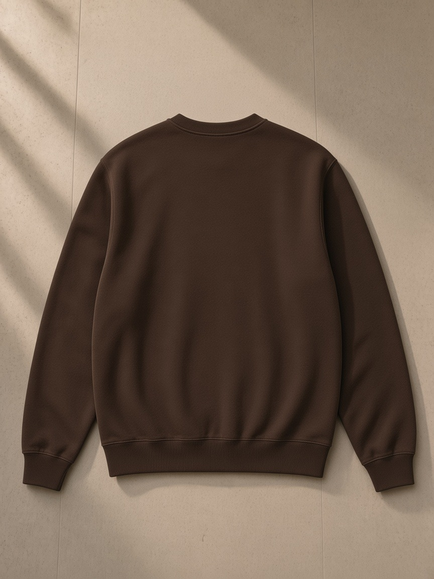 Unisex heavyweight crewneck sweatshirt in Coffee, laid flat on pale limestone, back view
