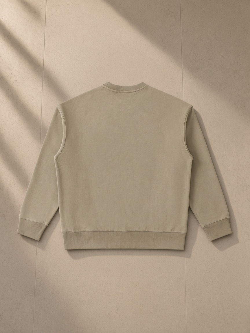 Heavyweight patch pocket crewneck sweatshirt in Khaki, laid flat on pale limestone, back view