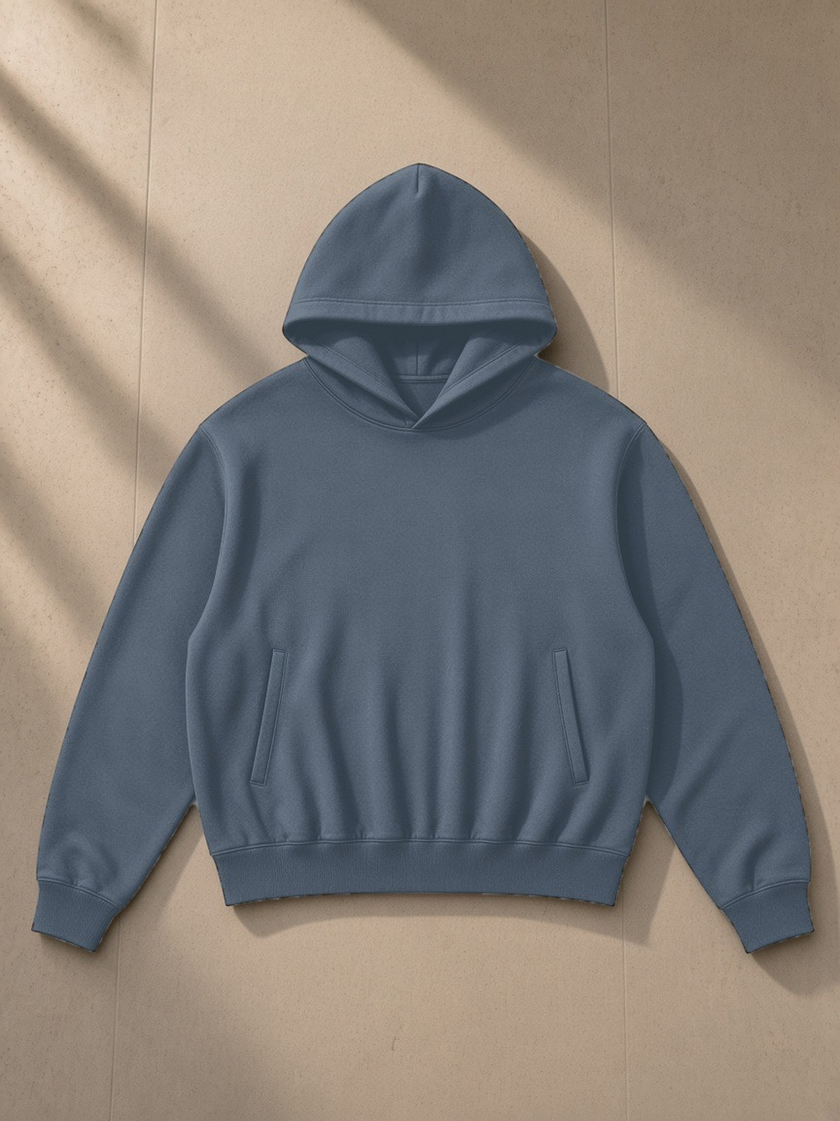 Oversized Drop Shoulder Hoodie in Blue, laid flat on pale limestone, front view