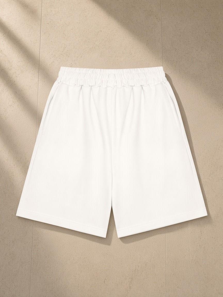 Unisex heavyweight shorts in White, laid flat on pale limestone