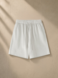 Vintage wash cotton shorts in Greyish White, laid flat on pale limestone