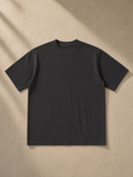 Unisex vintage wash drop shoulder t-shirt in Black, laid flat on pale limestone