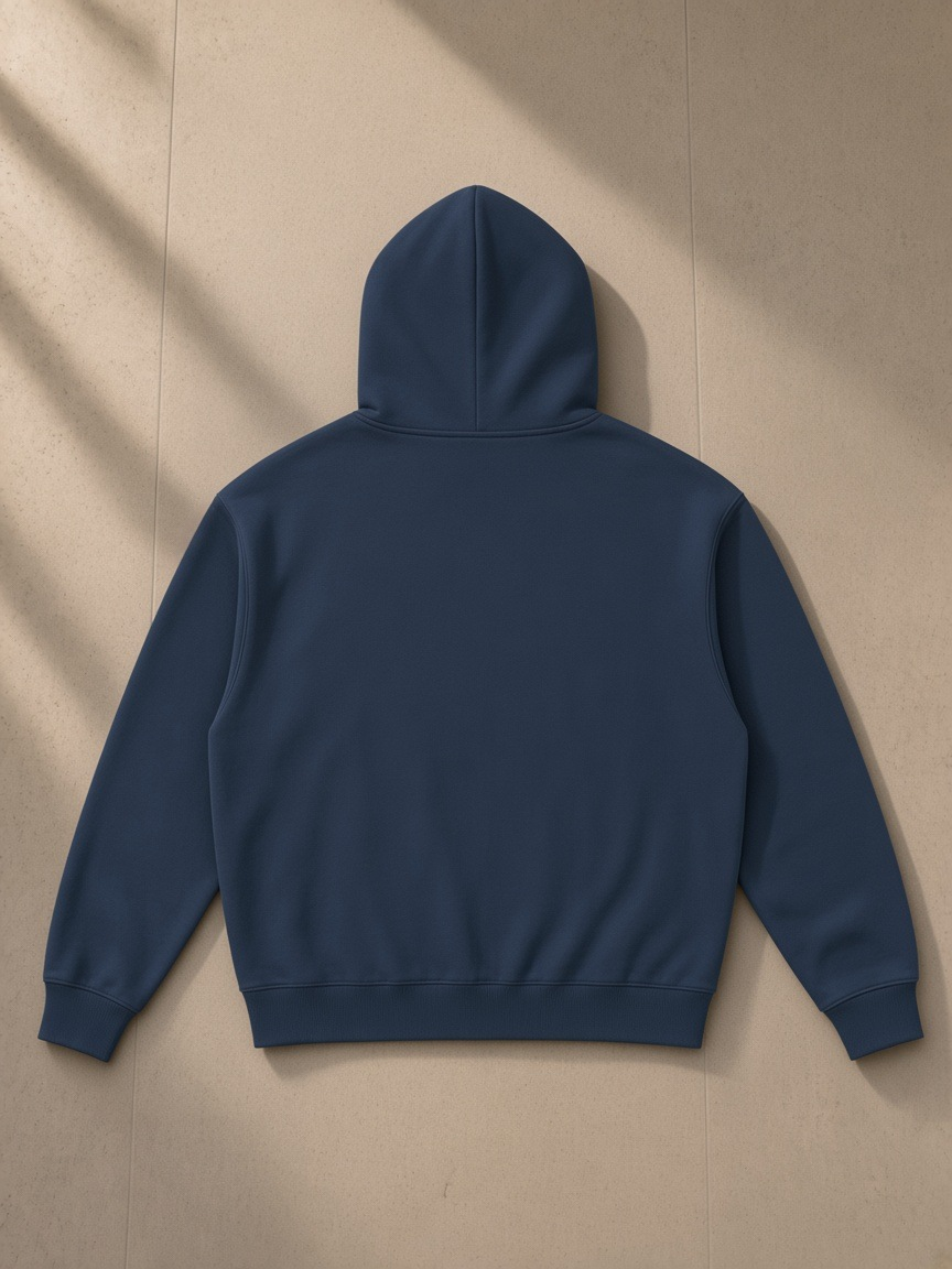Unisex loose full zip hoodie in Navy Blue, laid flat on pale limestone, back view