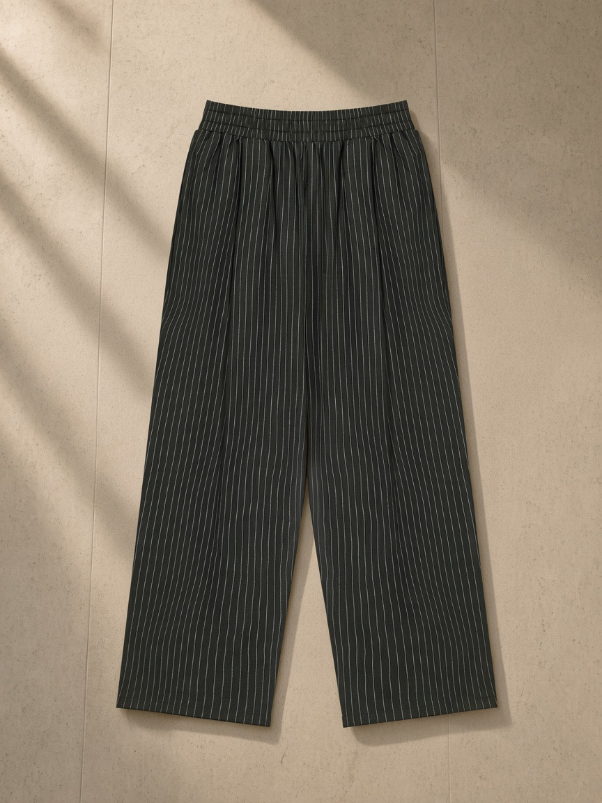 Striped Pleated Pants in Black, laid flat on pale limestone