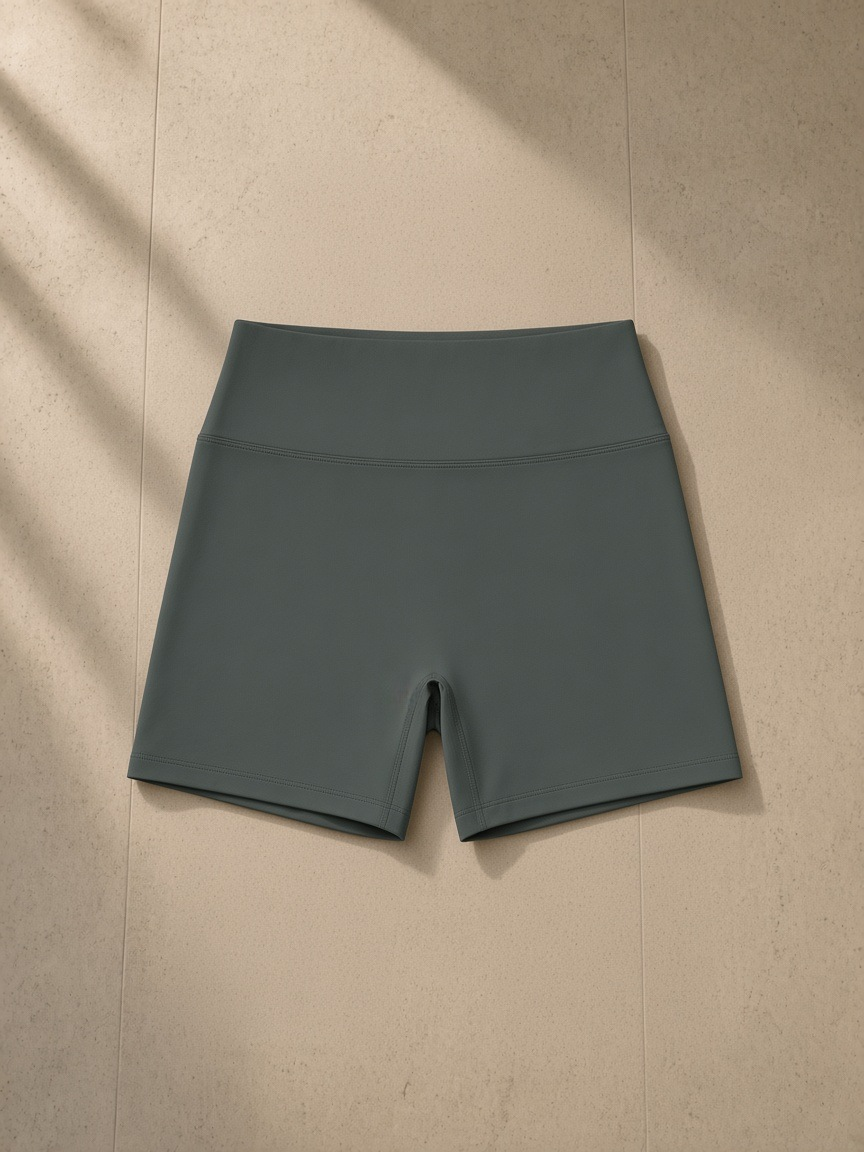 Women's High Rise Yoga Shorts in Dark Gray, laid flat on pale limestone