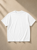 Unisex boxy drop shoulder t-shirt in White, laid flat on pale limestone