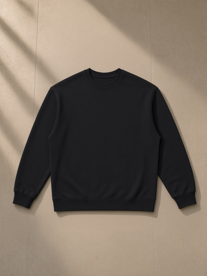 Oversized Crewneck Sweatshirt in Black, laid flat on pale limestone