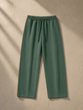 Vintage wash barrel leg fleece sweatpants in Dark Green, laid flat on pale limestone