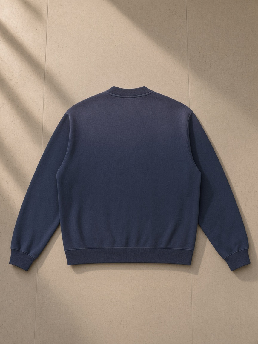 Sun fade heavyweight baseball jacket in Navy Blue, laid flat on pale limestone, back view