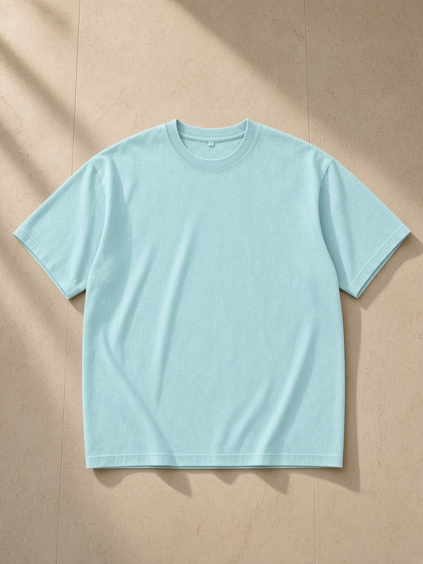 Unisex snow washed oversized cotton t-shirt in Water Blue, laid flat on pale limestone