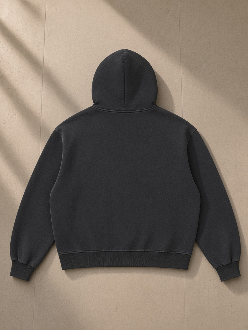 Vintage Wash Boxy Fleece Hoodie in Black, laid flat on pale limestone, back view