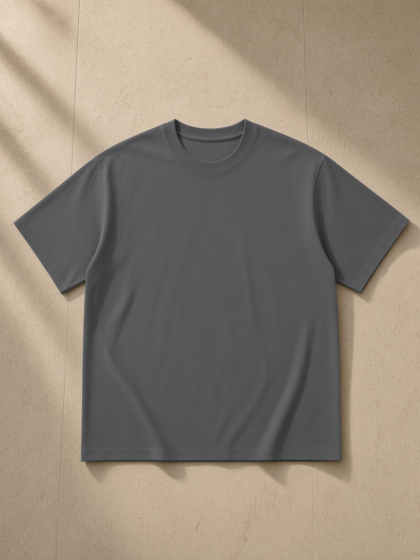 Unisex cotton t-shirt in Dark Gray, laid flat on pale limestone