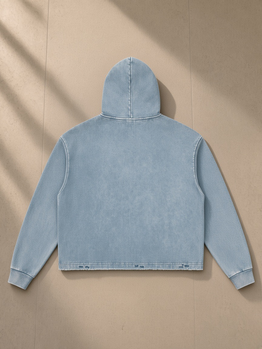 Vintage washed frayed-hem hoodie in Blue, laid flat on pale limestone, back view