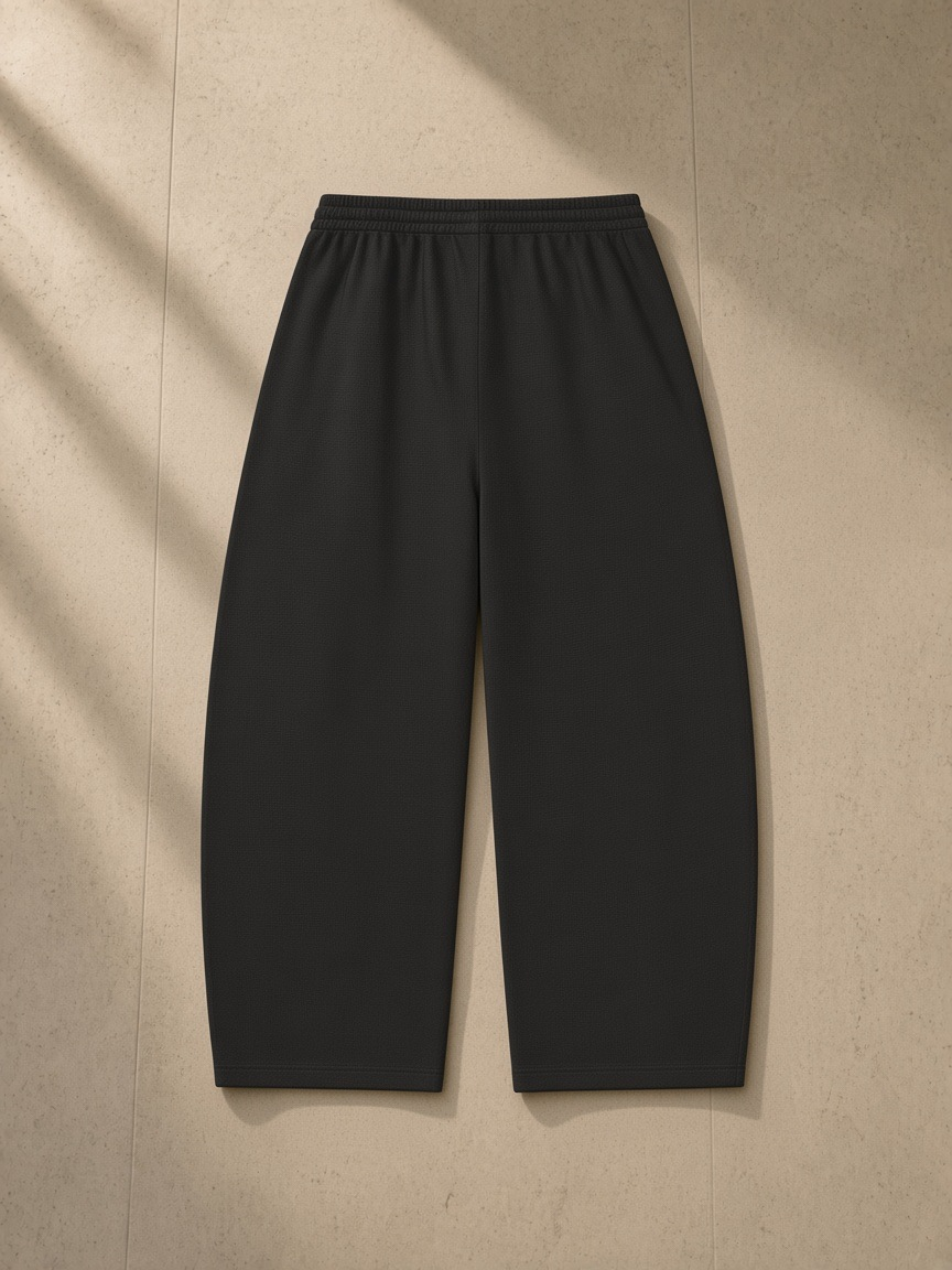 Waffle barrel leg pants in Black, laid flat on pale limestone, back view